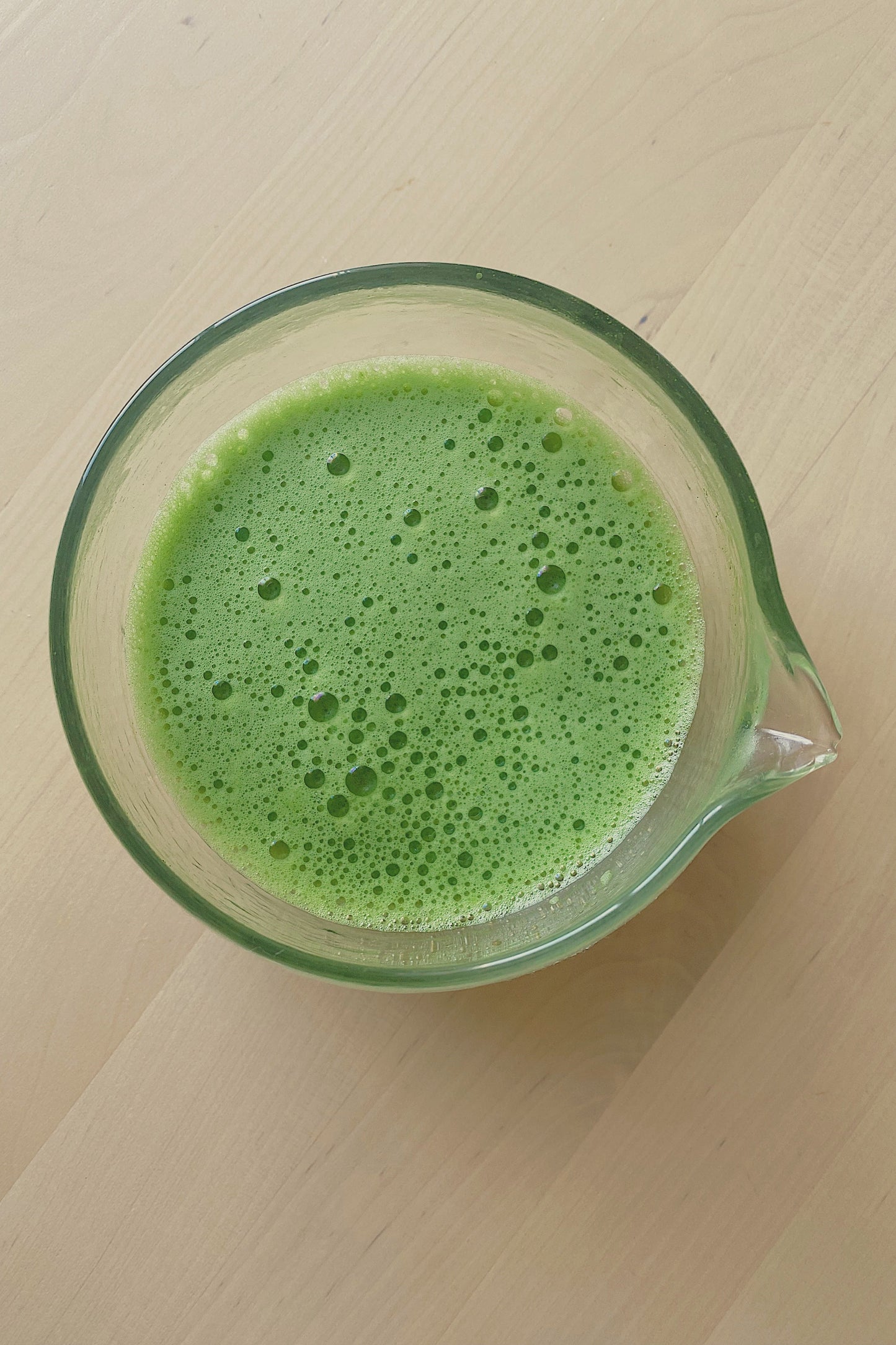 Freshly prepared ceremonial matcha in a glass matcha bowl with a smooth frothy texture. Japanese ceremonial matcha prepared in a glass bowl with a vibrant green colour and smooth foam