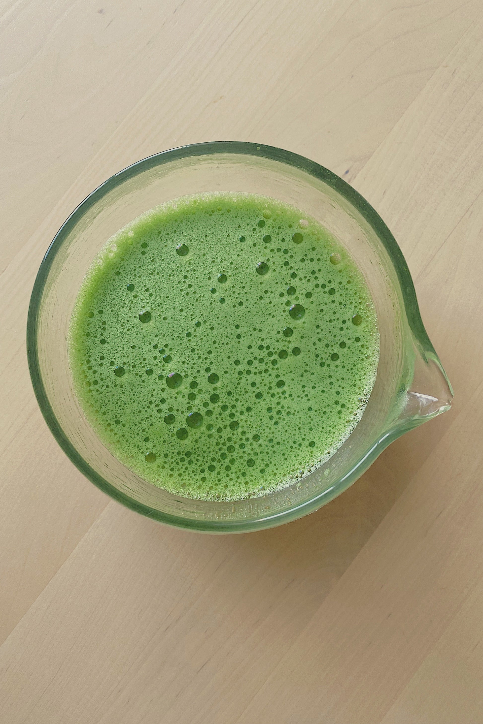 Freshly prepared ceremonial matcha in a glass matcha bowl with a smooth frothy texture. Japanese ceremonial matcha prepared in a glass bowl with a vibrant green colour and smooth foam