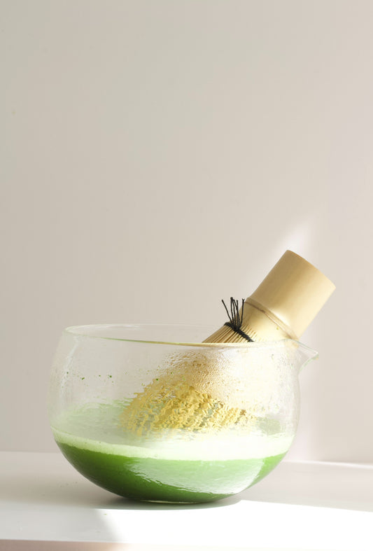 Glass matcha bowl with bamboo whisk ready for traditional matcha preparation. Glass matcha bowl and bamboo whisk used for traditional Japanese matcha preparation